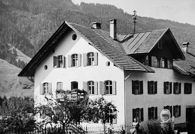 Schwarzweißaufnahme eines alten Haus vor Bergpanorama
