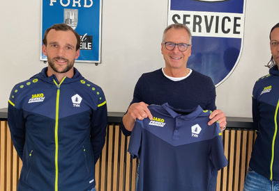 Drei Männer mit Präsentation der Trainingsjacken des Fußballvereins mit neuem Logoaufdruck des Autohaus Fersch
