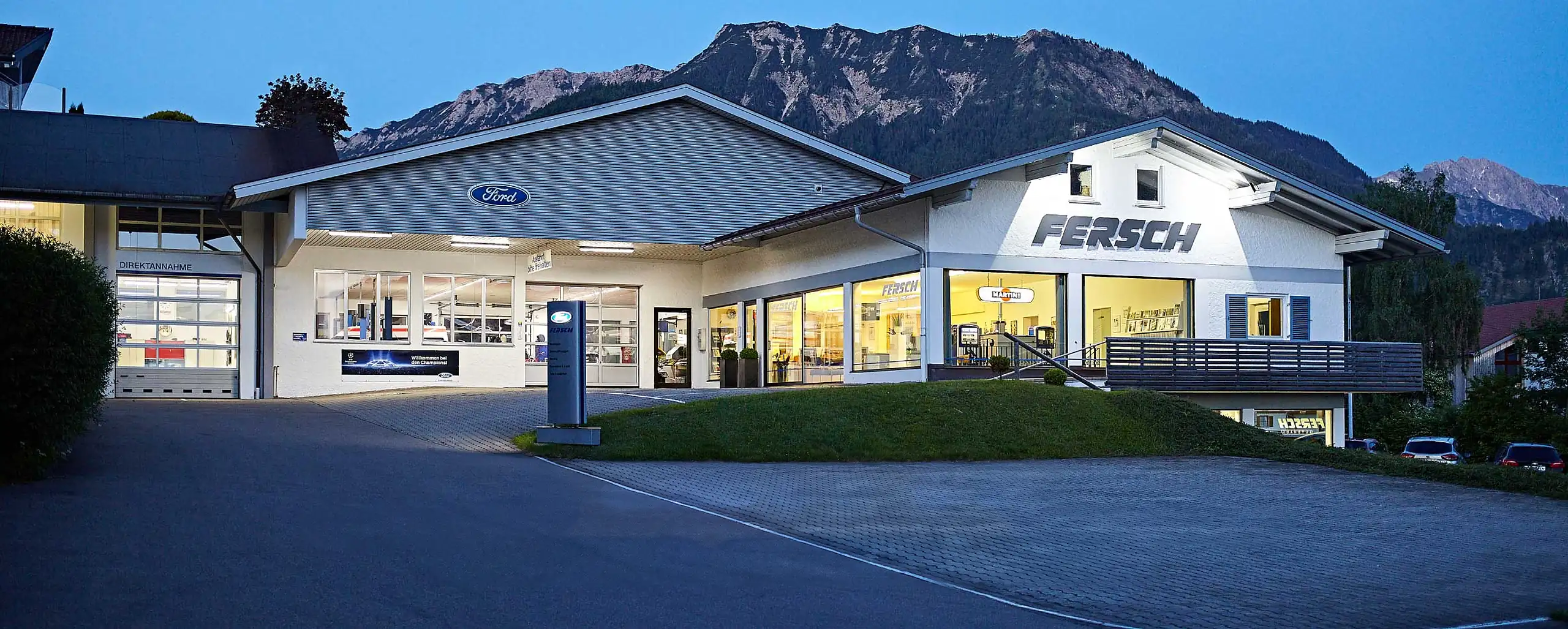Das Autohaus Fersch in Bad Hindelang in der Abenddämmerung vor den Allgäuer Bergen